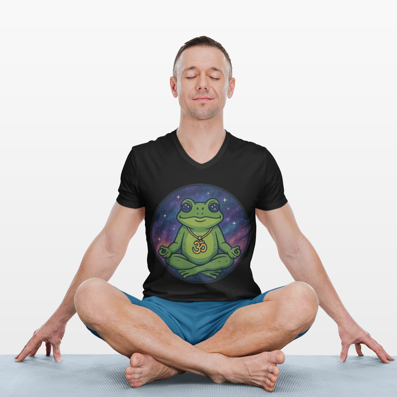 Man sitting in a meditative pose wearing a black t-shirt with a green frog design on a white background