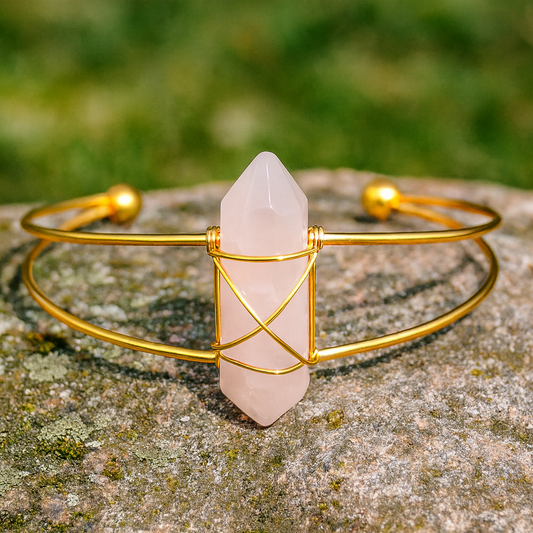 Gold bracelet with a pink crystal on a stone surface